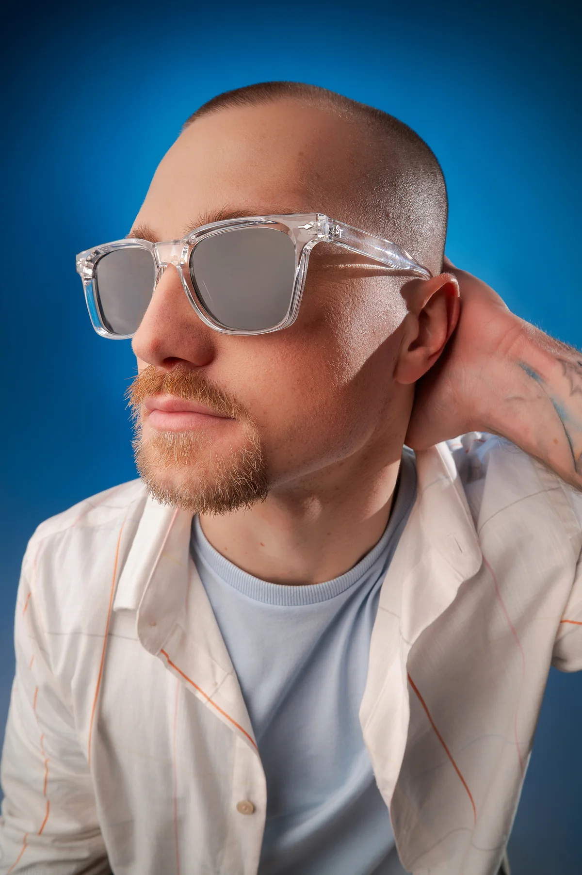Homem usando armação transparente com lentes escuras diante de fundo azul