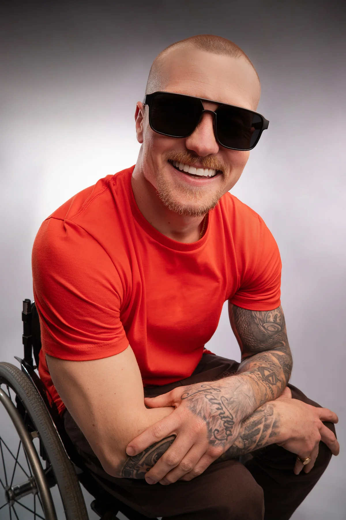 Homem sorrindo com óculos escuros e camiseta vermelha